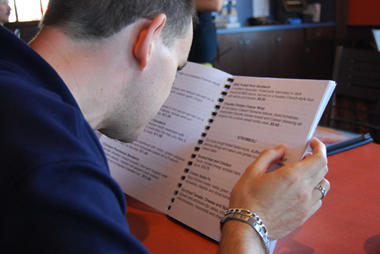 Marc reading a large-print menu in a restaurant.