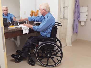 Elderly man washing his hands in an accessible washroom.